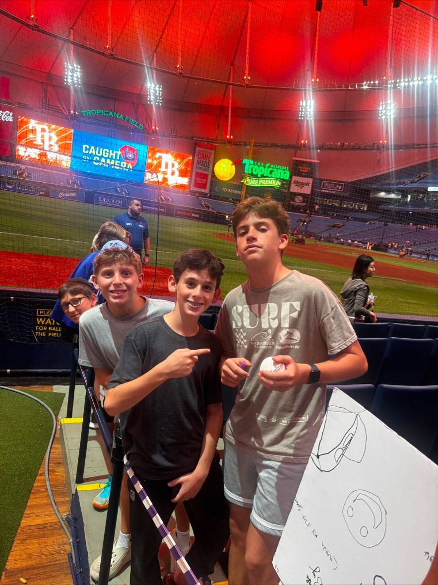 Campers in the stands holding a baseball and a handmade sign