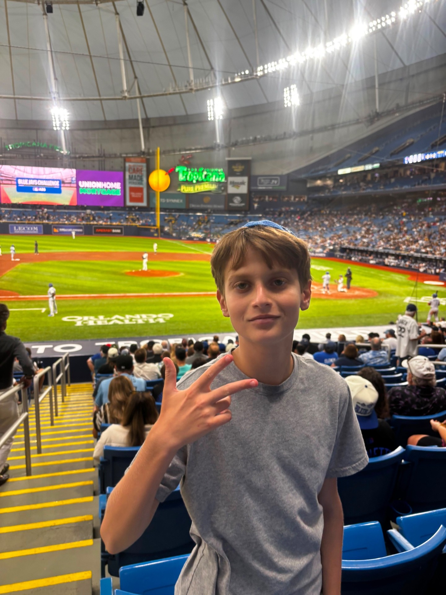 A camper posing in the stands at an indoor baseball game