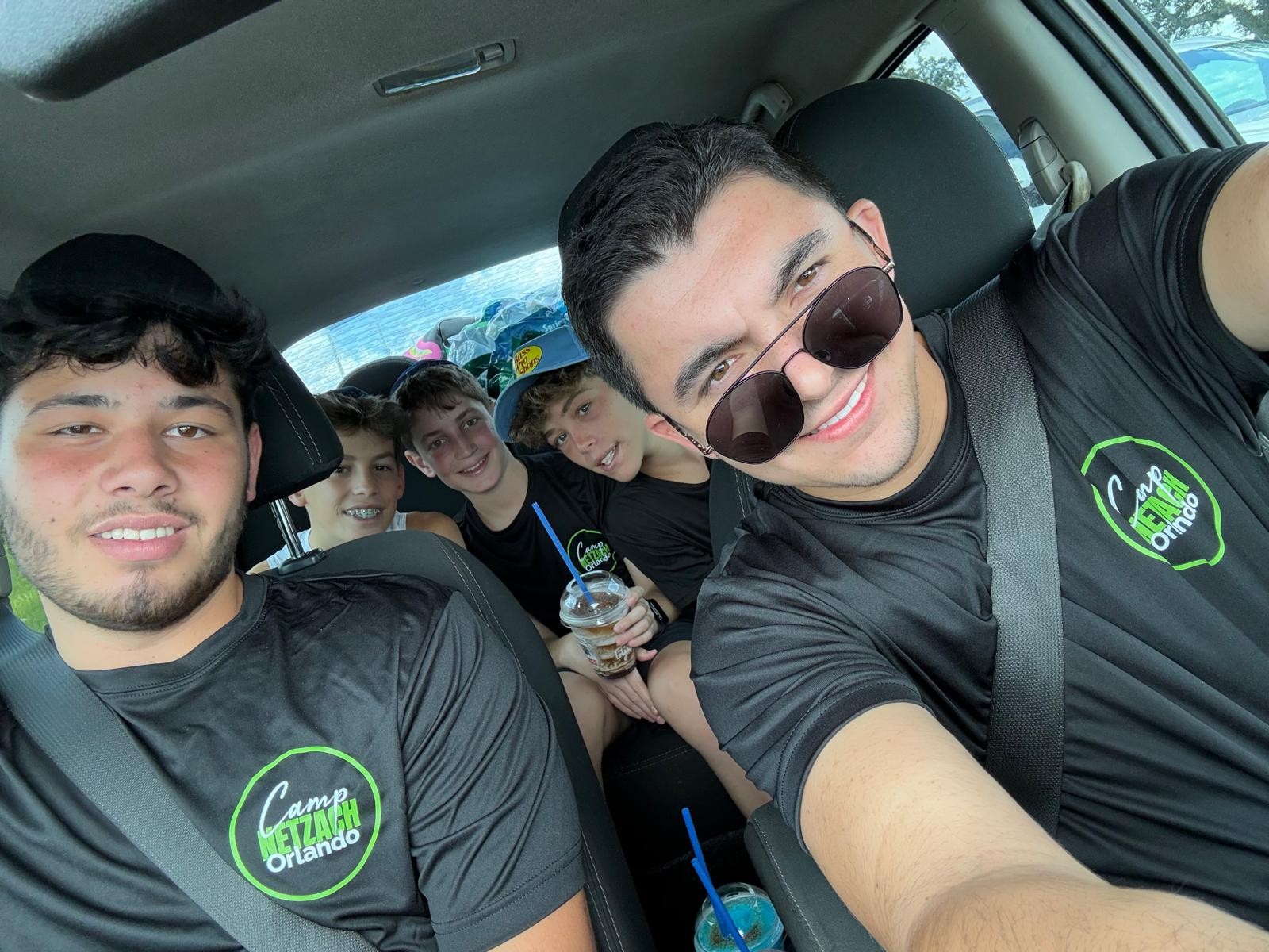 Campers in matching camp shirts taking a selfie together in a car