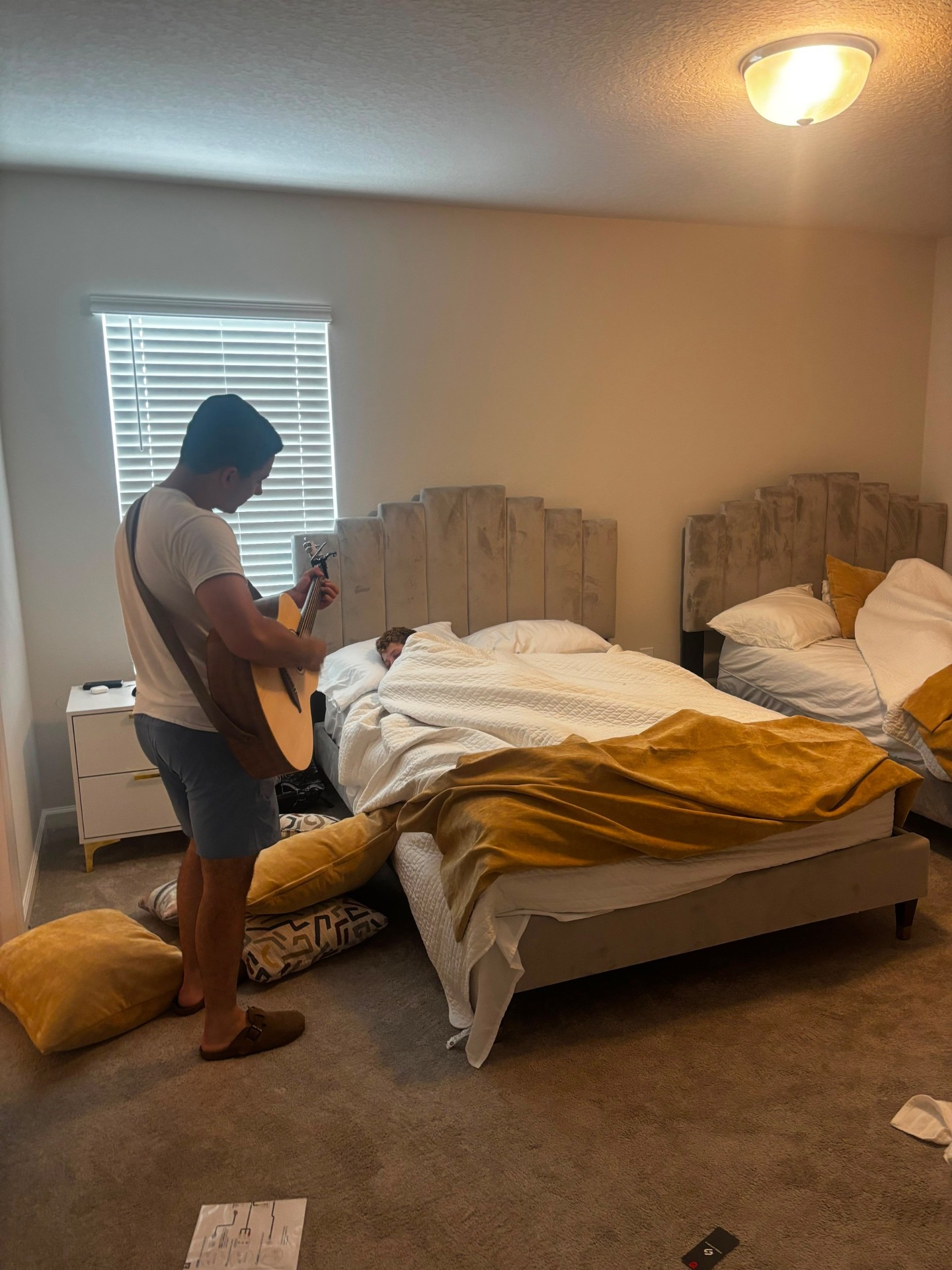 A counselor playing guitar beside a camper's bed