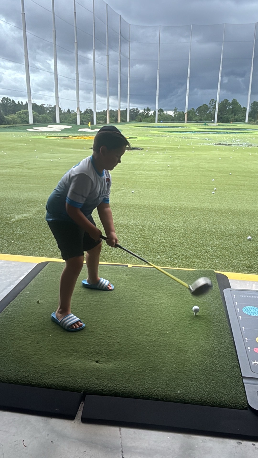 A camper swinging a golf club at an outdoor driving range