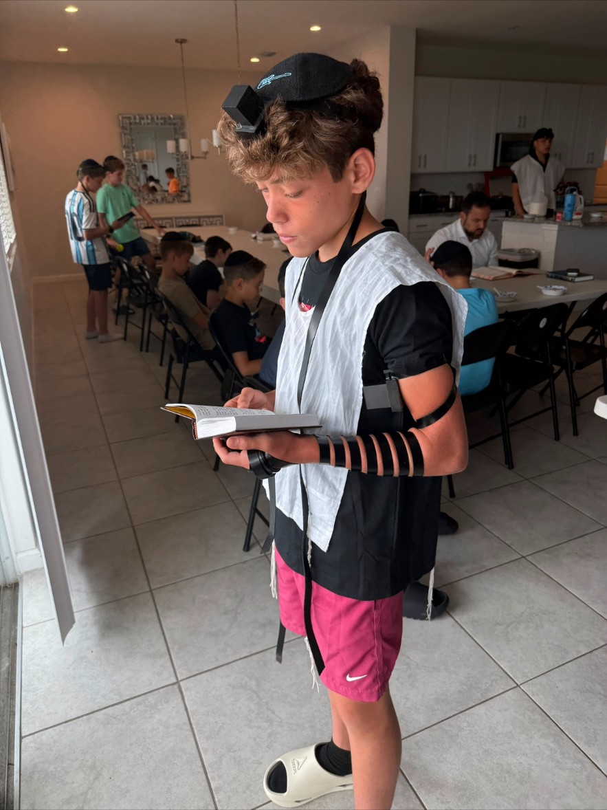 Campers learning together with prayer books around tables