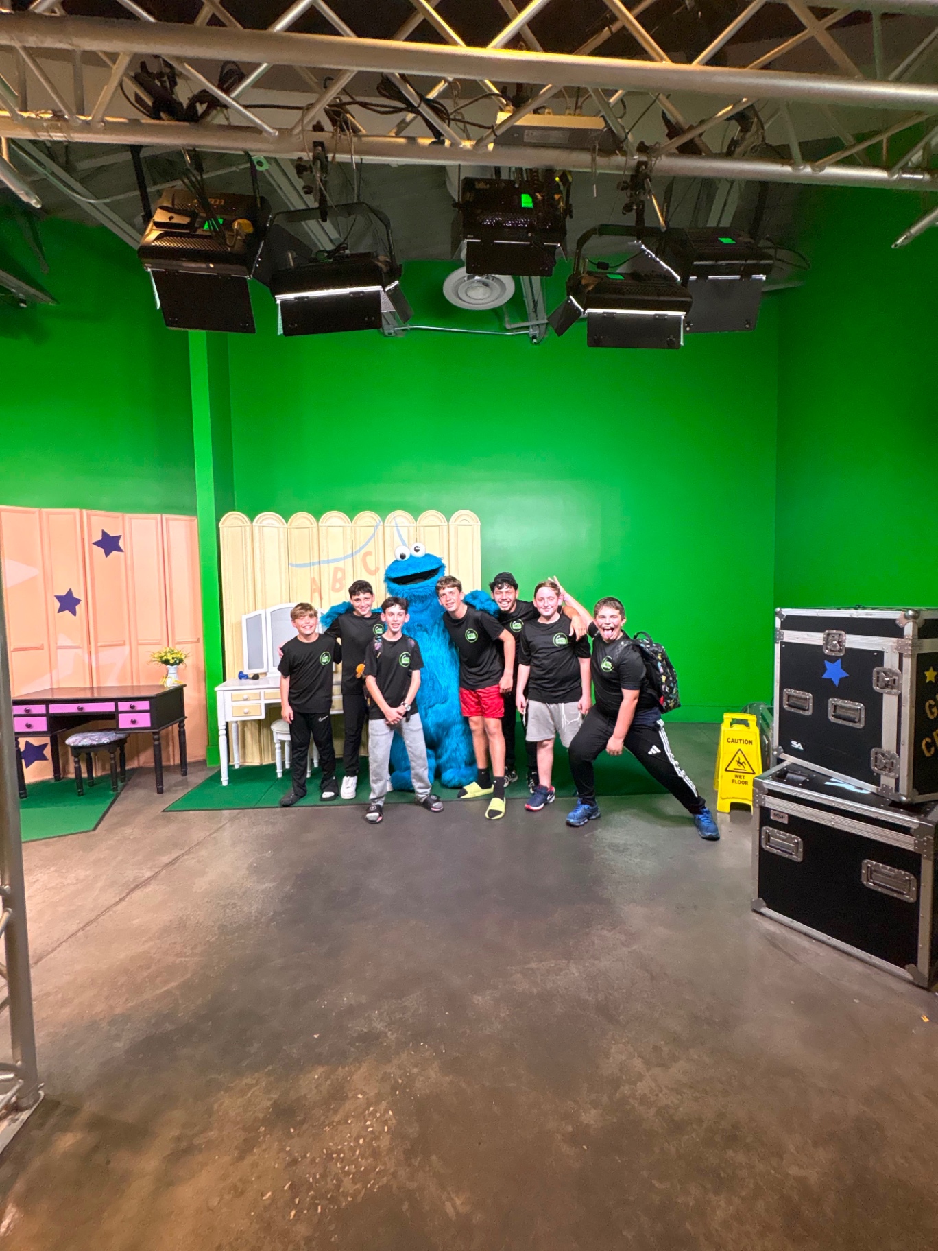 Campers in matching shirts posing with Cookie Monster in a television studio