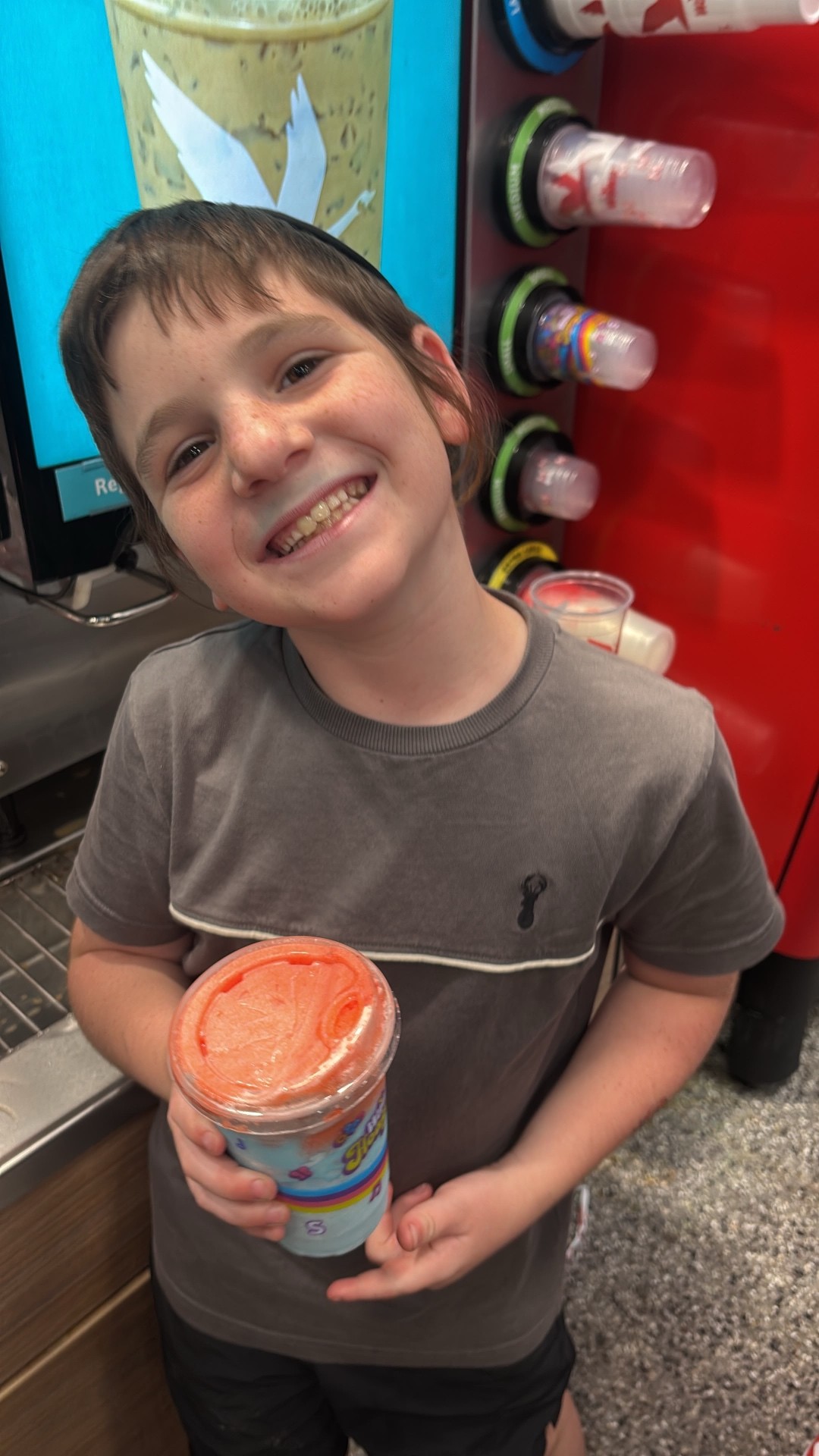 A smiling camper holding a frozen slushie drink