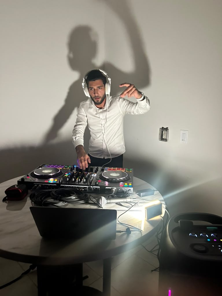 A DJ with headphones mixing music on a controller at a camp party