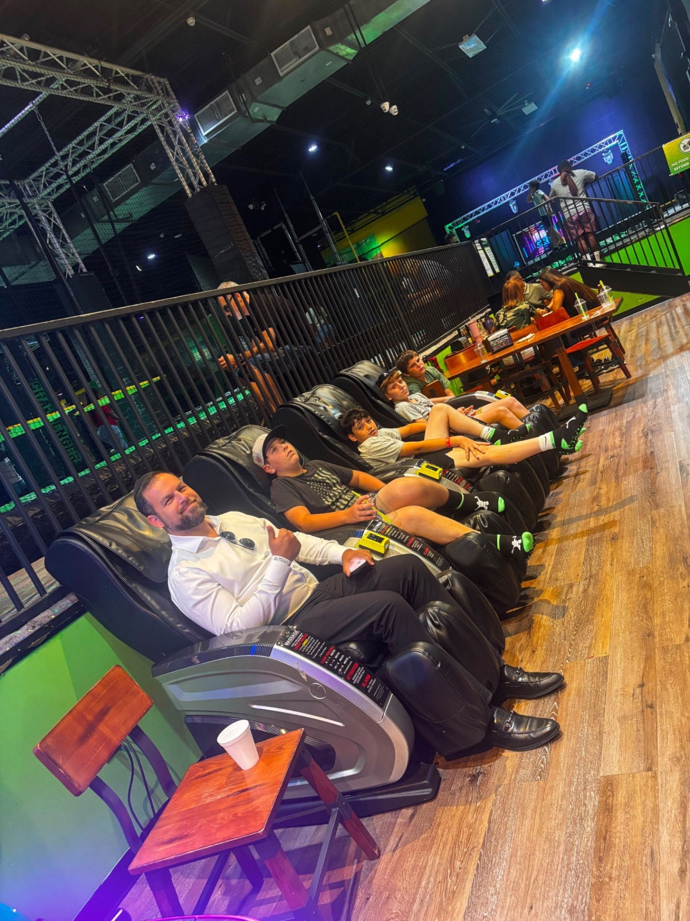 A counselor and four campers sitting together in a row of massage chairs