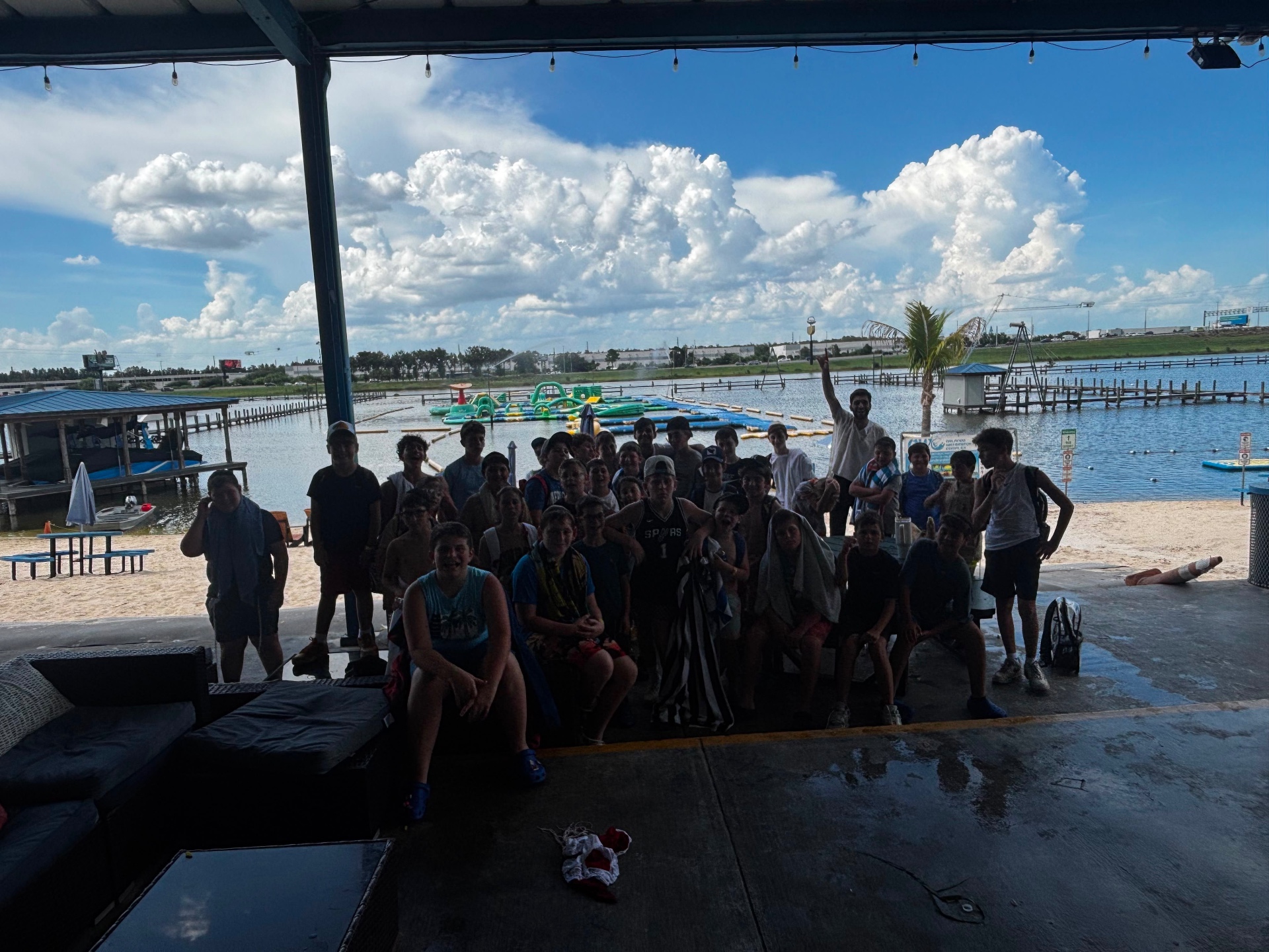 Campers posing under a pavilion overlooking a lake with an inflatable waterpark