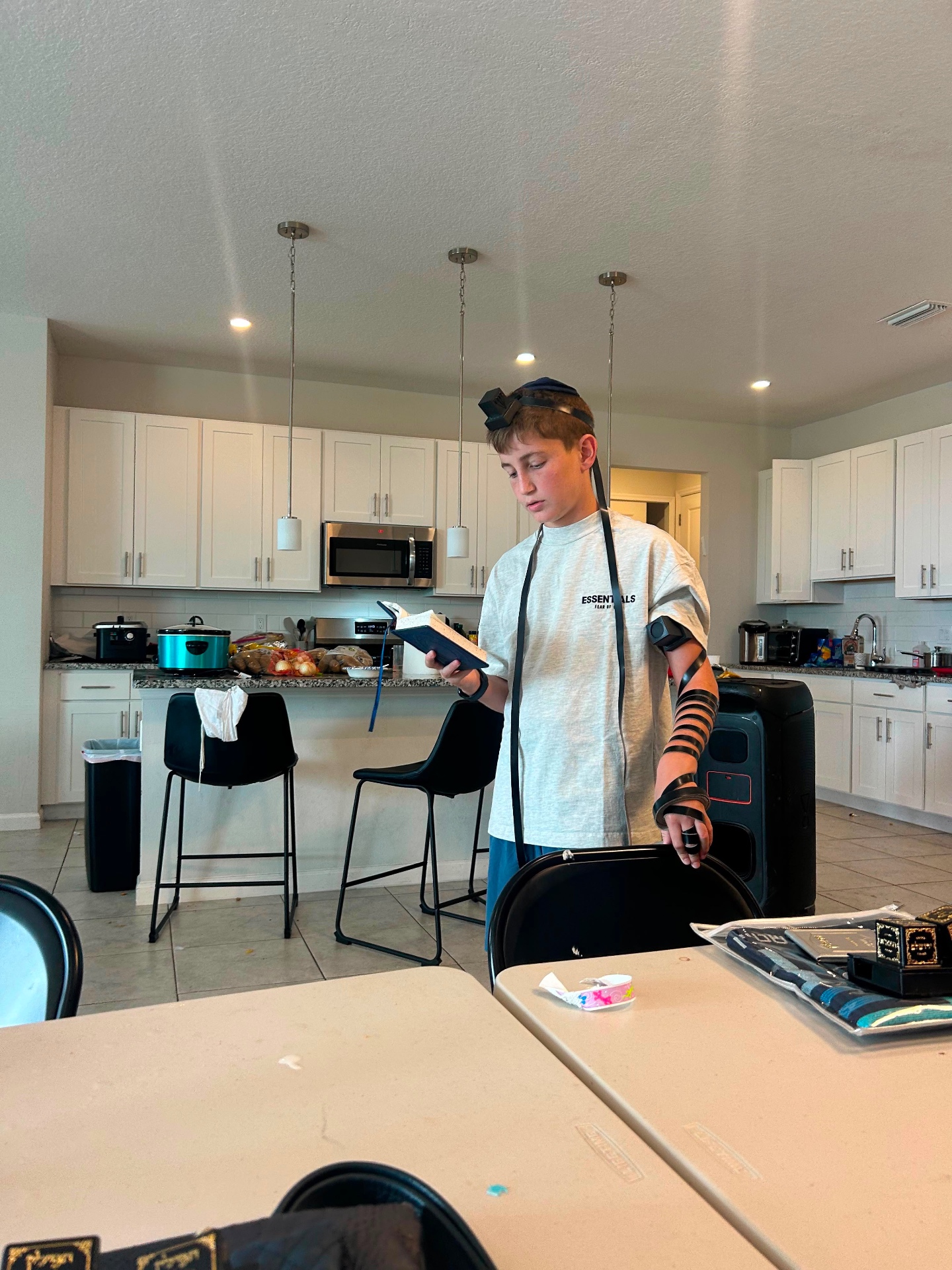 A camper wearing tefillin reading from a prayer book