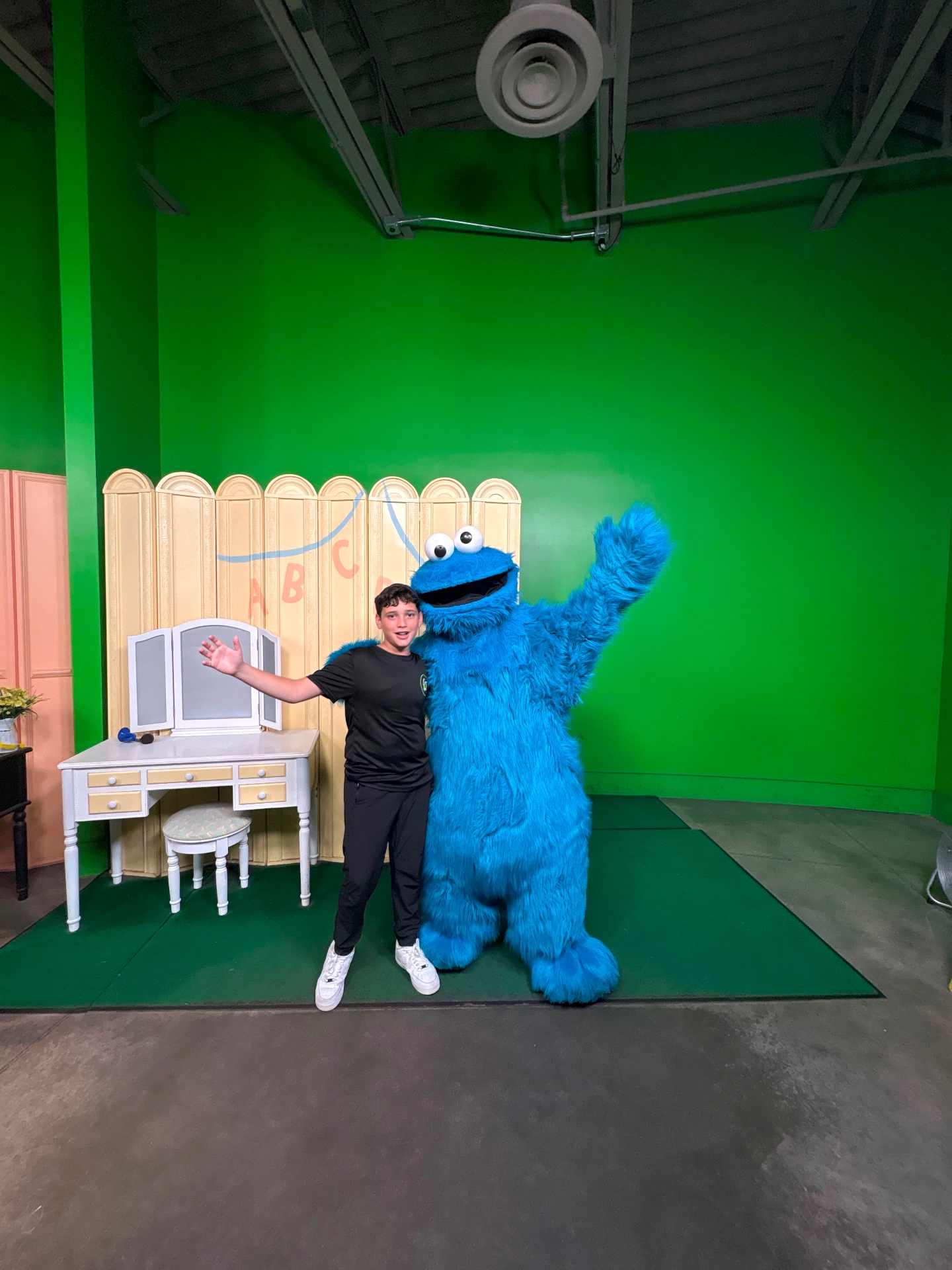 A camper posing beside Cookie Monster in front of a green screen