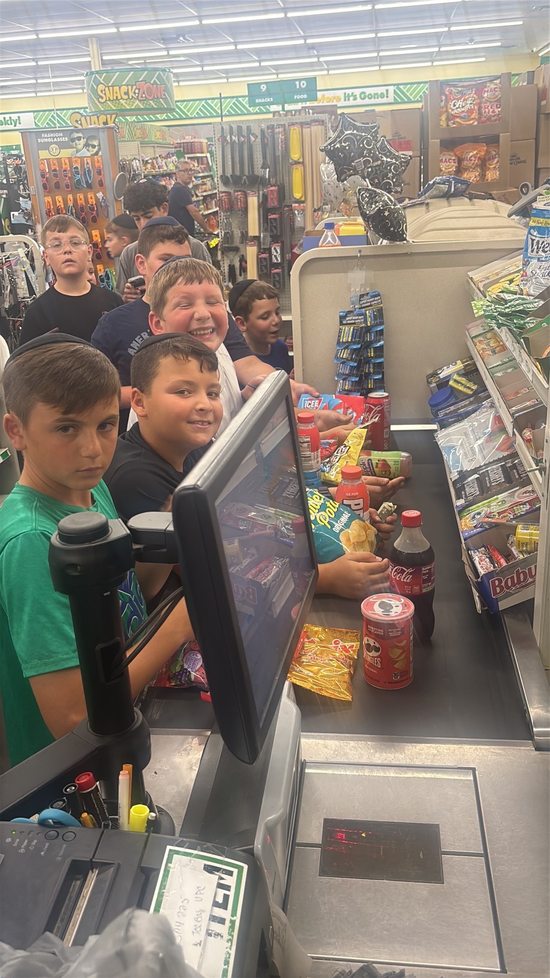 Campers laughing together at a store checkout counter full of snacks and drinks