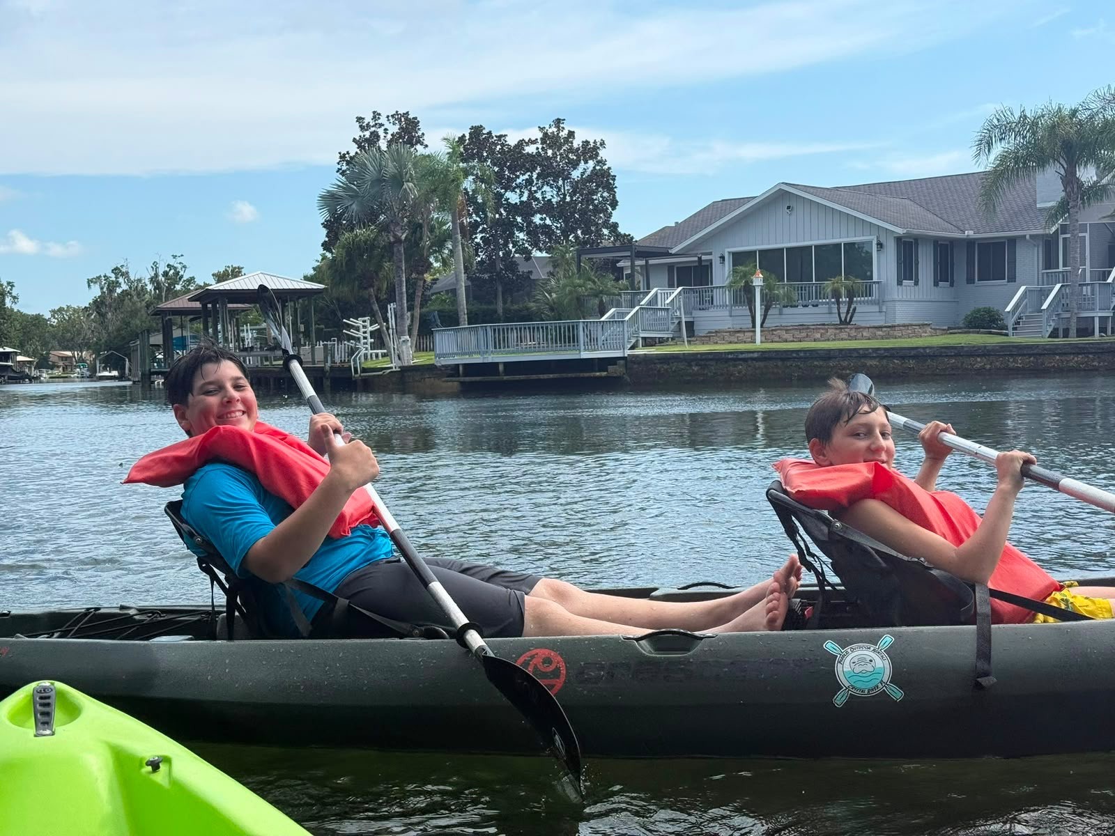 Two campers paddling a tandem kayak in red life vests