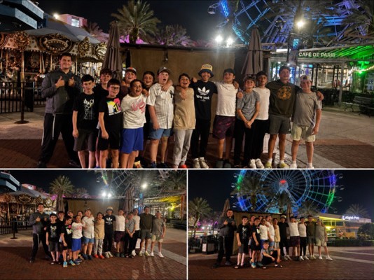 Campers and counselors posing at night beneath an illuminated Ferris wheel