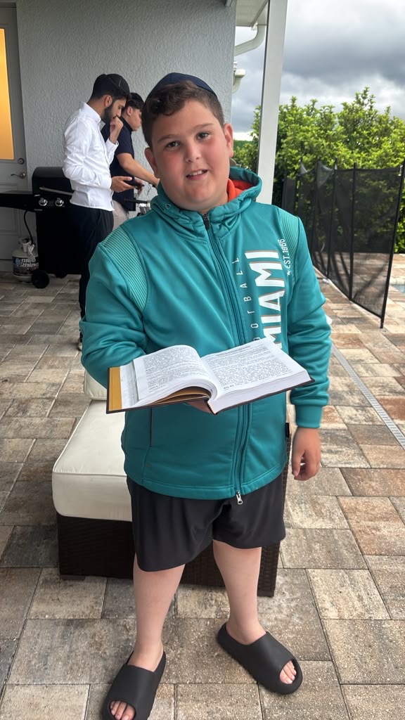 A camper smiling with an open prayer book on a sunny patio