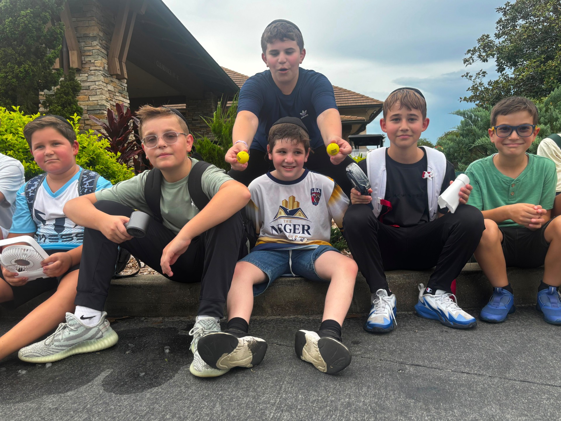 Campers sitting together outdoors holding golf balls and small fans