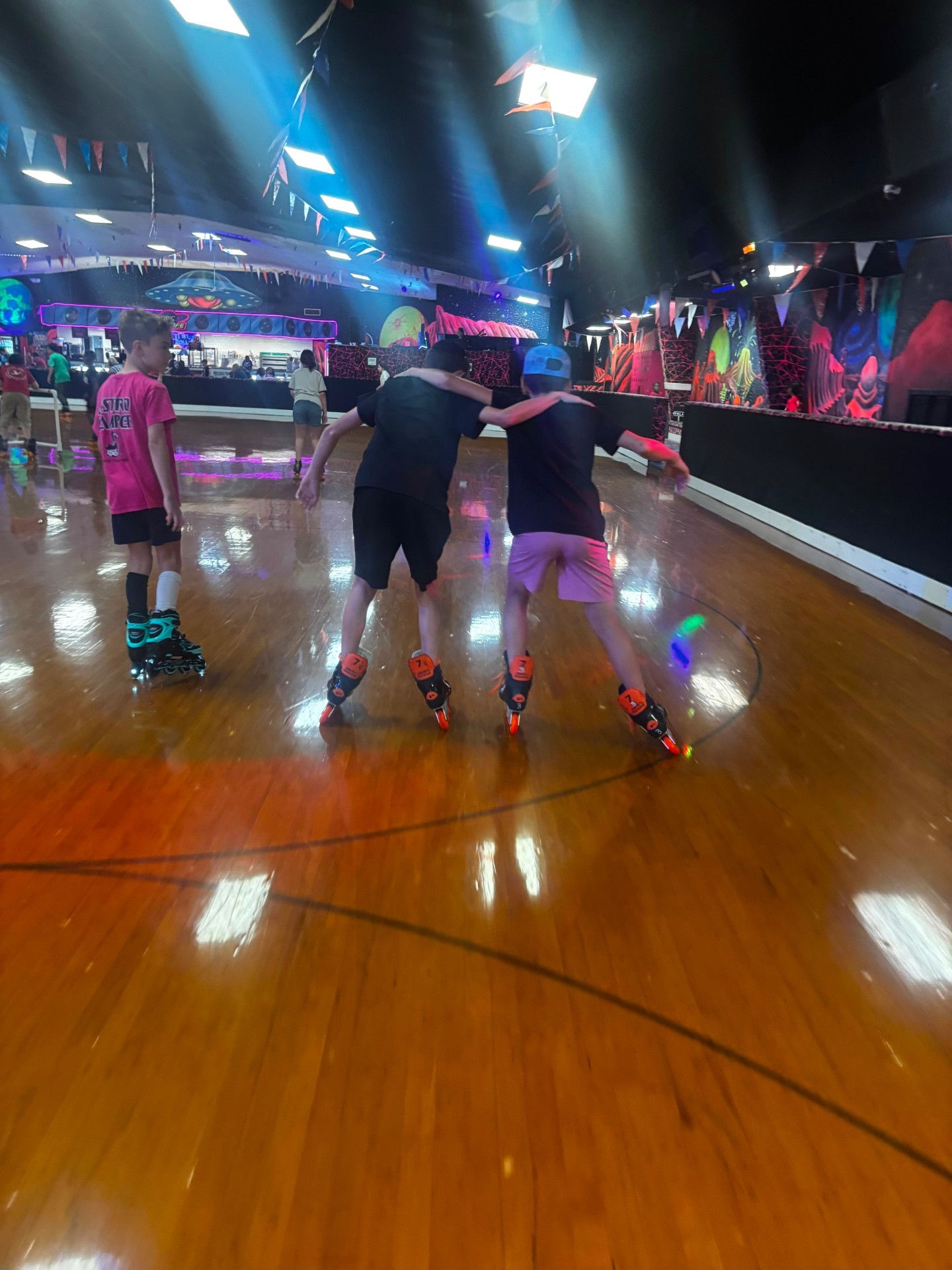 Two campers skating arm in arm across a glowing roller rink