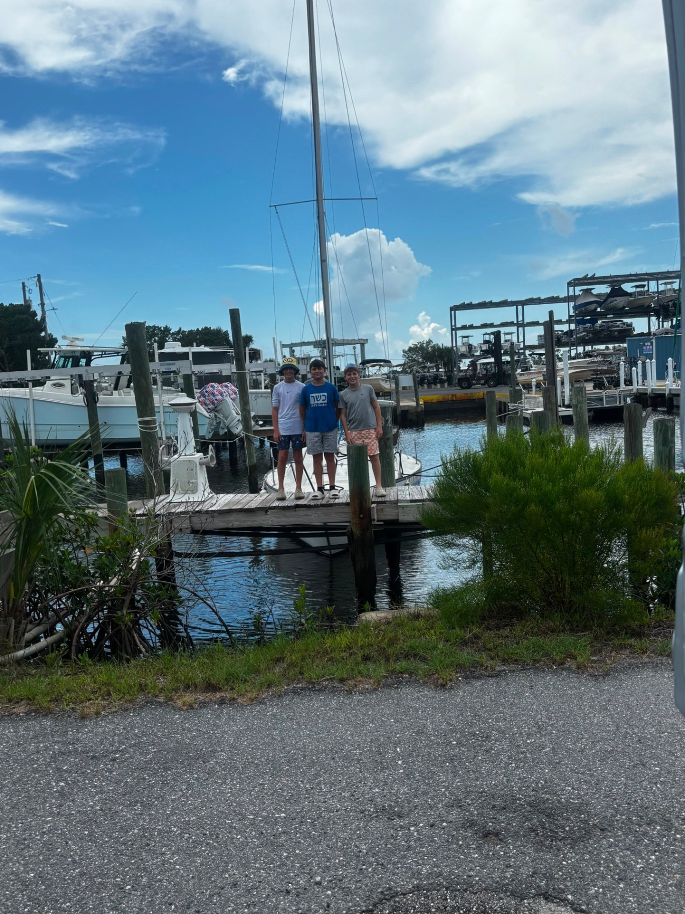 Three campers standing on a wooden dock in front of a marina full of boats