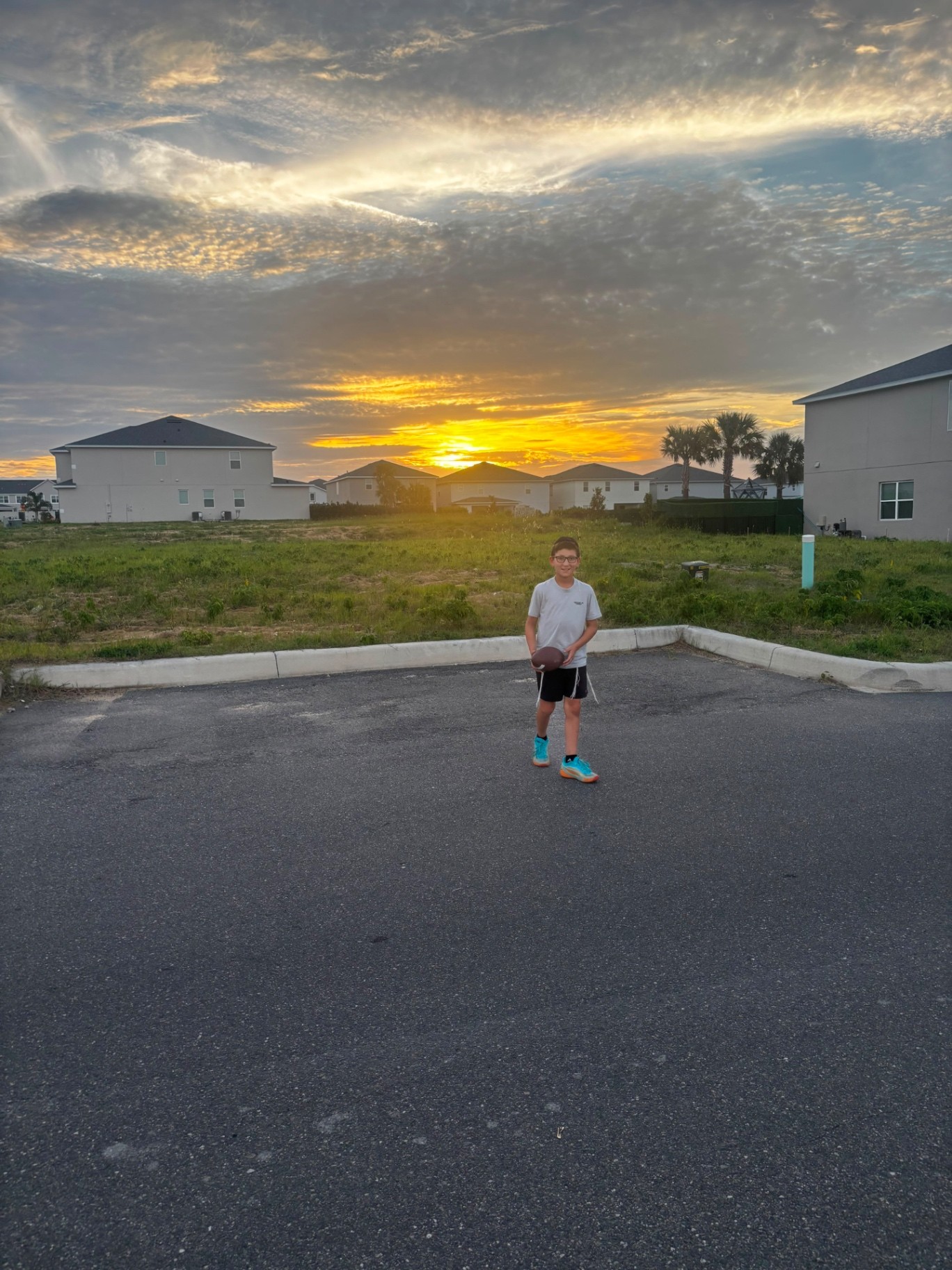 A camper holding a football at sunset in front of a grassy field